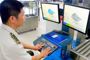 Nhân viên an ninh kiểm tra hành lý qua máy soi tại sân bay Nội Bài
