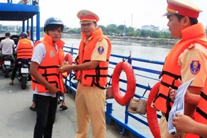 Cảnh sát giao thông đường thủy TPHCM hướng dẫn khách đi phà mặc áo phao để đảm bảo an toàn