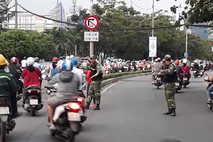 Các nhân viên bảo vệ của cao ốc gần cầu Sài Gòn ra đường phân luồng cho xe máy lưu thông qua làn đường dành cho ô tô Ảnh: ĐOÀN HIỆP