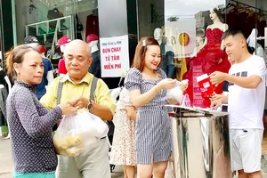 Một phụ nữ nghèo (bìa trái) nhận suất ăn sáng cho cả nhà từ nhóm bạn anh Huỳnh Nghĩa