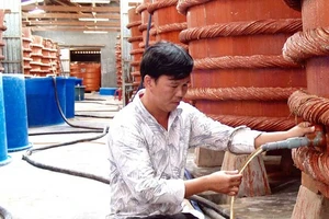 Kiểm tra chất lượng nước mắm trong quá trình rút kéo nước mắm bên trong nhà thùng tại Phú Quốc. Ảnh: NGỌC CHÁNH