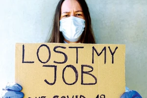 Một người lao động thất nghiệp ở Mỹ cầm tấm bìa ghi: Tôi mất việc làm vì Covid-19