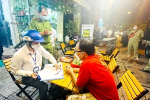 Đoàn kiểm tra phường 3 (quận Gò Vấp) lập biên bản một chủ quán bán rượu bia cho thực khách vào đêm 2-11. Ảnh: VĂN MINH