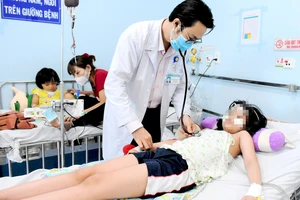 TS-BS Nguyễn Minh Tuấn, BV Nhi đồng 1 TPHCM, thăm khám cho bệnh nhi L.N.N.Q (Ảnh chụp chiều 24-3) 