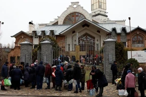 Người dân Kherson xếp hàng nhận hỗ trợ thực phẩm và nước bên ngoài một nhà thờ ngày 22-11. Ảnh: REUTERS