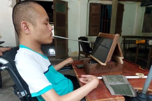 Anh Phạm Sỹ Long ngồi xe lăn ngậm bút tự chế viết truyện trên máy tính bảng