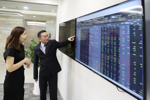 Ông Trương Hiền Phương, Giám đốc cấp cao, Công ty chứng khoán KIS Việt Nam cùng đối tác nghiên cứu diễn biến thị trường chứng khoán. Ảnh: HOÀNG HÙNG