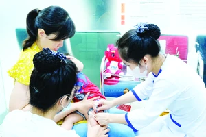 Nhân viên y tế tại một trung tâm tiêm chủng tiêm vaccine cho trẻ