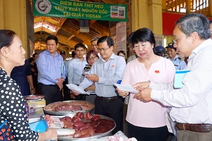 Đoàn giám sát HĐNDTP kiểm tra giấy chứng nhận nguồn gốc thịt heo tại chợ Bến Thành. Ảnh: HOÀNG HÙNG