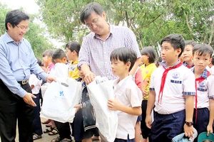 PGS-TS Trần Văn Ngọc (bìa trái) và bác sĩ Cao Xuân Minh tặng quà học sinh Trường Tiểu học Tân Hòa