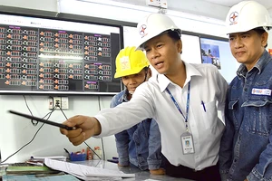 Kỹ sư Đỗ Tiến Trung (giữa) và đồng nghiệp giám sát hệ thống lưới điện tại Trung tâm quản lý lưới điện Hóc Môn