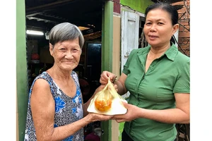 Chị Huỳnh Thị Phẩm mang bữa ăn đến tận nhà cho bà Lê Thị Mai 