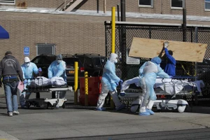 Nhân viên y tế đưa thi thể bệnh nhân qua đời ra khỏi bệnh viện Wyckoff Heights ở Brooklyn, New York, Mỹ hôm 6-4. Ảnh: Reuters