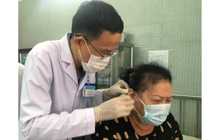 ThS-BS Nguyễn Văn Đàn thực hiện phương pháp nhĩ châm cho bệnh nhân bị nhức mỏi. Ảnh: MINH NAM