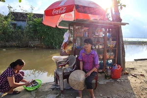 Chị Lê Thị Trang bên quán tạp hóa nhỏ ven bờ kênh. Ảnh: MINH PHONG