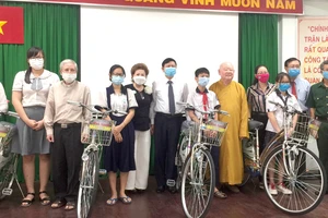 Chị Đặng Thị Minh Nguyệt (thứ tư, từ trái sang) tặng phương tiện đi học cho học sinh, sinh viên hoàn cảnh khó khăn