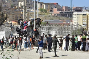 Người di cư trèo qua hàng rào biên giới tại Fnideq, Maroc, để sang vùng Ceuta của Tây Ban Nha ngày 18-5-2021. Ảnh: THX