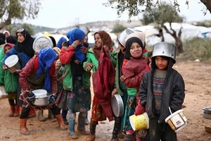 Trẻ em xếp hàng nhận thực phẩm cứu trợ tại một trại tị nạn ở tỉnh Aleppo, Syria