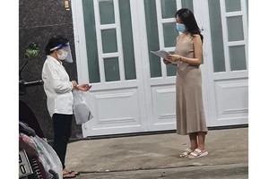  Bà Lê Thị Ngọc Bối (trái), Tổ trưởng Tổ 46 (khu phố 3, phường 19, quận Bình Thạnh) đến nhà phát phiếu đăng ký tiêm vaccine cho người dân