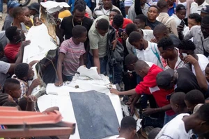 Người dân tập trung quanh đống đổ nát của chiếc máy bay lao xuống một con phố đông đúc tại Haiti. Ảnh: Reuters