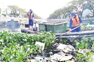 Công nhân Công ty Môi trường đô thị TPHCM vớt rác trên tuyến kênh Tân Hóa - Lò Gốm