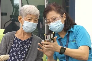 Tình nguyện viên hướng dẫn cụ Pauline Tong sử dụng các ứng dụng chăm sóc sức khỏe