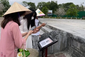 Du khách quét mã QR trên điện thoại thông minh để ngắm điện Thái Hòa qua tour du lịch thực tế ảo