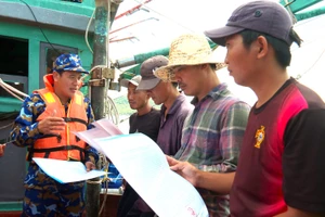 Thành viên đoàn công tác Vùng 5 Hải quân phát thư kêu gọi chống khai thác IUU cho ngư dân. Ảnh: VĂN ĐỊNH