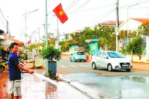Người dân ấp 1, xã Bình Sơn, huyện Long Thành xịt nước nhằm hạn chế bụi bẩn bay vào nhà
