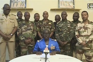 Đại tá Amadou Abdramane (ngồi), Người Phát ngôn của Hội đồng Quốc gia Bảo vệ Tổ quốc (CNSP) tại Niger, tuyên bố đảo chính trên truyền hình quốc gia ngày 26-77