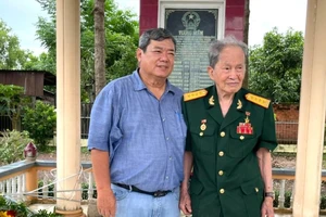 Anh hùng Lực lượng vũ trang nhân dân Tư Cang cùng tác giả trước tấm bia tưởng niệm các chiến sĩ cách mạng hy sinh tập thể tại xã Long Phước, TP Bà Rịa, tỉnh Bà Rịa - Vũng Tàu