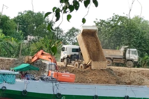 Xe xúc đất bùn từ các xe tải chở đến lên các sà lan chờ sẵn bên mé kênh Hồng Ngự - Vĩnh Hưng (huyện Tân Hưng, Long An)