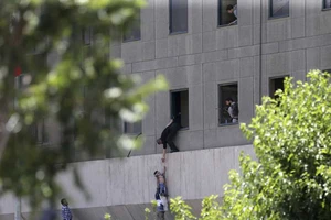 Đưa một đứa trẻ ra khỏi tòa nhà Quốc hội Iran trong vụ tấn công ngày 7-6-2017. Ảnh: AP