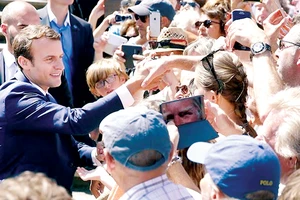 Tổng thống Pháp Emmanuel Macron (trái) gặp gỡ cử tri sau khi bỏ phiếu