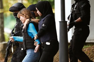 Đoàn Thị Hương (áo xanh) mặc áo chống đạn và được áp tải khỏi tòa hôm 13-4. Ảnh: Reuters.