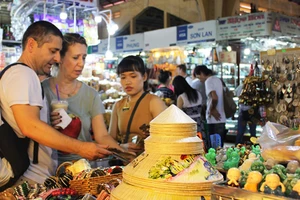Du khách nước ngoài đang chọn mua các mặt hàng thủ công mỹ nghệ, quà lưu niệm tại chợ Bến Thành Ảnh: Gia Hân