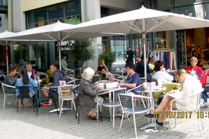 Người dân ngồi sưởi nắng uống cà phê trong một tiệm cà phê ngoài trời tại Đức