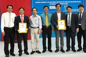 Ông Phạm Văn Tám (áo xanh), Trưởng Ban Quản lý Khu kinh tế tỉnh Trà Vinh trao giấy chứng nhận cho nhà đầu tư Dự án Nhà máy điện gió Duyên Hải