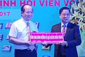 Viện sĩ, GS-TS Hoàng Quang Thuận (áo trắng) trao 100 triệu đồng cho Chủ tịch Câu lạc bộ ủng hộ đồng bào bị thiệt hại do cơn bão số 10 gây ra.