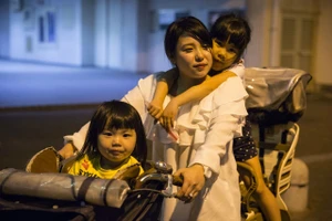 Masami Onishi, 23 tuổi, cùng với các con gái của mình, Yua, 3 tuổi và Sora, 6 tuổi, trên một chiếc xe đạp. Ảnh chụp khi họ đến Nishinari Kids' Dining Hall, nơi có thể vui chơi và nhận được đồ ăn miễn phí của nhóm cộng đồng