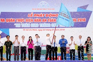 Chủ tịch UBND TPHCM Nguyễn Thành Phong trao cờ phát động ra quân thực hiện năm An toàn giao thông 2018. Ảnh: QUỐC HÙNG