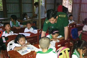 Thượng úy Trần Bình Phục đang hướng dẫn từng con chữ cho các cháu lớp học tình thương trên đảo Hòn Chuối(thị trấn Sông Đốc, huyện Trần Văn Thời, tỉnh Cà Mau).
