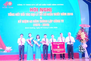 Ông Nguyễn Hoàng Thao (bìa trái), Phó Bí thư Thường trực Tỉnh ủy và ông Đặng Minh Hưng (bìa phải), Phó Chủ tịch UBND tỉnh trao Cờ thi đua của Thủ tướng Chính phủ cho Công ty TNHH MTV Xổ số kiến thiết Bình Dương