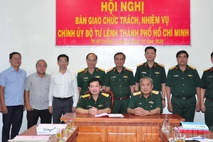Thiếu tướng Nguyễn Minh Hoàng (thứ 4 từ bên phải sang) và các đại biểu chứng kiến Thiếu tướng Ngô Tuấn Nghĩa và Đại tá Phan Văn Xựng ký biên bản bàn giao. Ảnh: hcmcpv