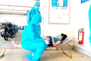 2 bác sĩ khám thai một cư dân trong khu vực phong tỏa. Ảnh: KHÁNH HƯNG