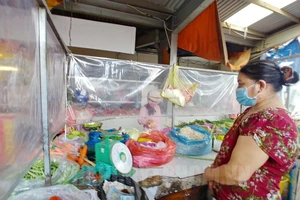Tiểu thương bán hàng ở chợ truyền thống làm vách ngăn bảo đảm điều kiện an toàn phòng chống dịch. Ảnh: hcmcpv