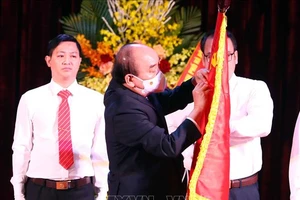 Chủ tịch nước Nguyễn Xuân Phúc gắn Huân chương Lao động hạng Nhất lên lá cờ truyền thống của Trường Đại học Sư phạm Hà Nội. Ảnh: TTXVN