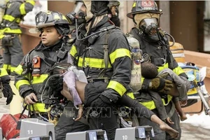Lính cứu hỏa sơ tán các em nhỏ tại hiện trường vụ hỏa hoạn. Ảnh: Nydailynews.com/TTXVN