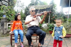 Chú Nguyễn Đăng Khoa ngồi kéo violon trước sân nhà