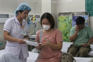 Nhân viên Trung tâm y tế quận Sơn Trà hướng dẫn người dân thanh toán viện phí bằng mã QR. Ảnh: XUÂN QUỲNH